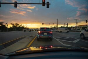 American wide multilane street intersection with traffic lights and moving cars.