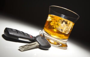 Alcoholic drink and car keys under spot light.