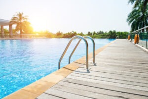 Swimming pool with stair and wooden deck at hotel.