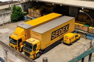 Yellow SEDEX delivery trucks parked behind the Correios package delivery center waiting for cargo at the loading bay.